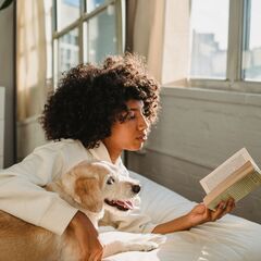 Pet parent reading beside her dog